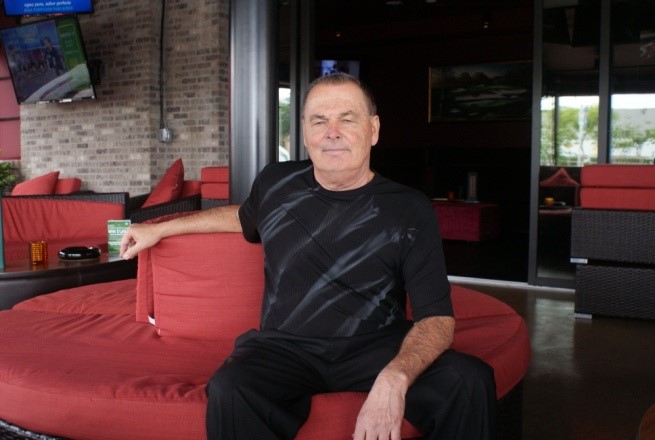 Proprietor Dewey Tomko lounges in the expansive patio of Dewey’s Indoor Golf & Sports Grill.